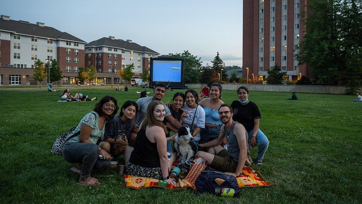 A group of students sitting on a blanket in the grass at the U of I campus