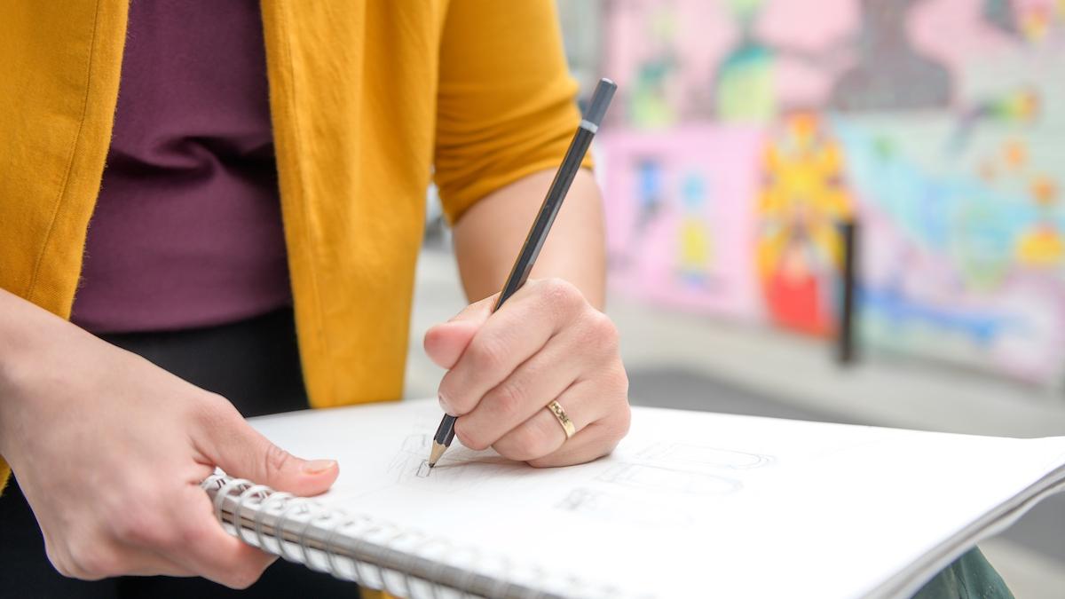 A student sketches in a notebook.